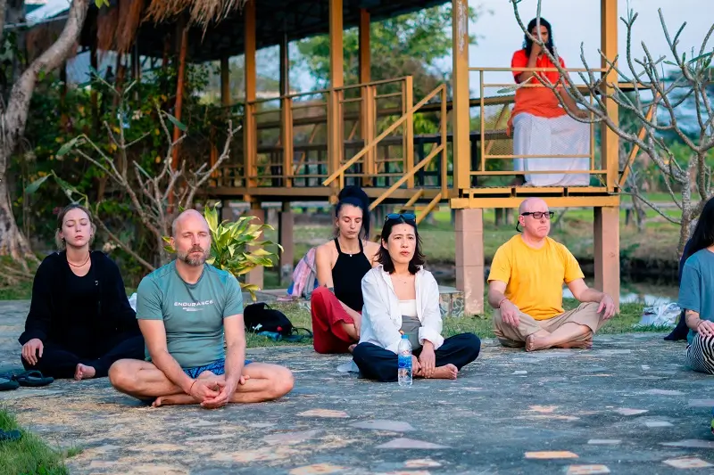 Guests sitting in meditation outdoors at dusk