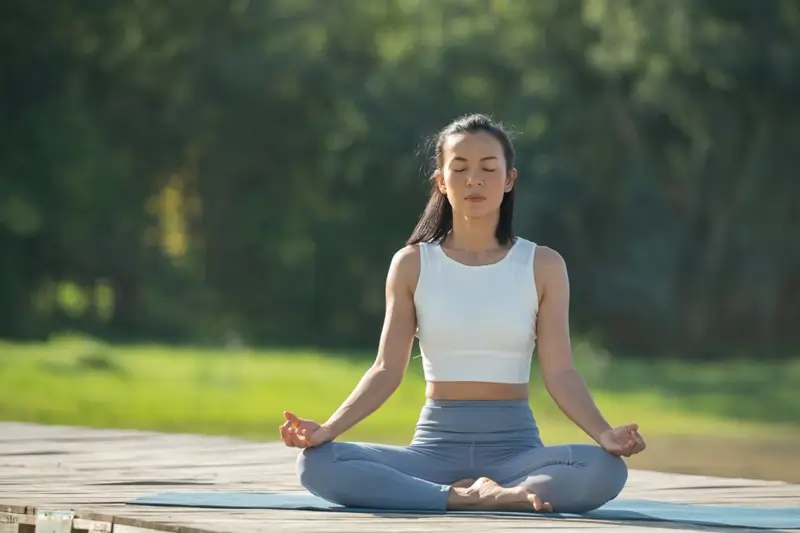 Woman practicing Sukhasana (Easy Pose) outdoors