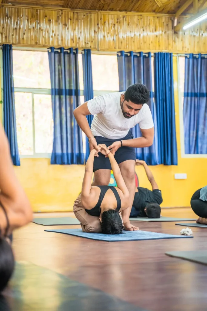 Yoga teacher assisting student in backbend